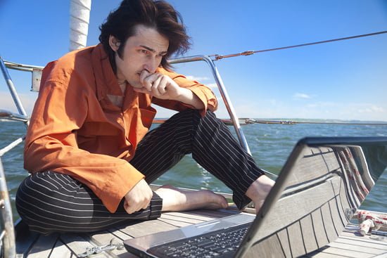 Businessman with laptop computer on sailboat
